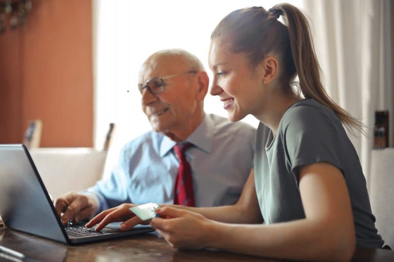 young woman helping elderly use a laptop computer