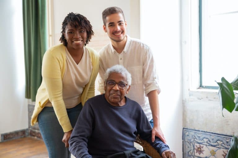 two young person helping an elderly in wheelchair